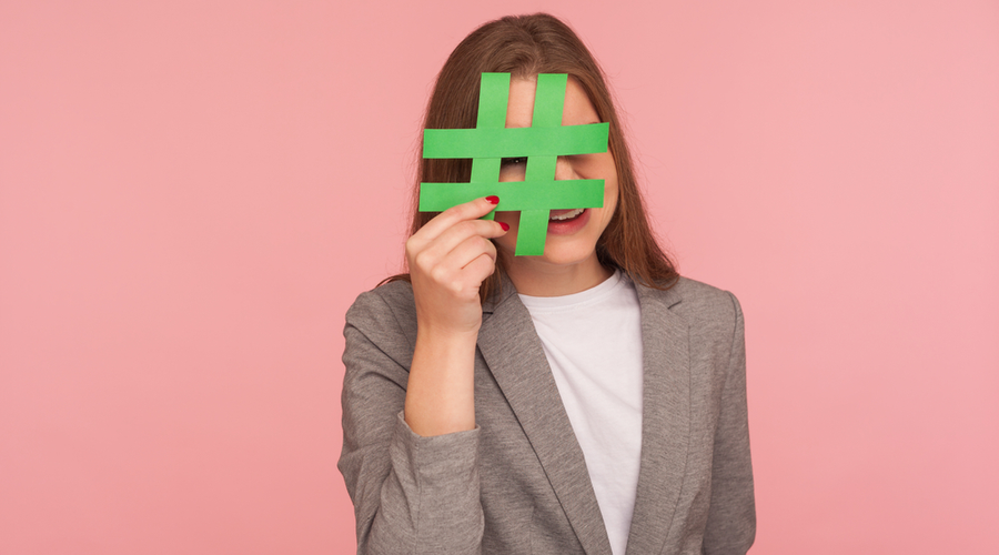 Woman holding hashtag over face against pink background