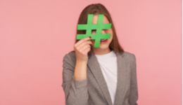 Woman holding hashtag over face against pink background