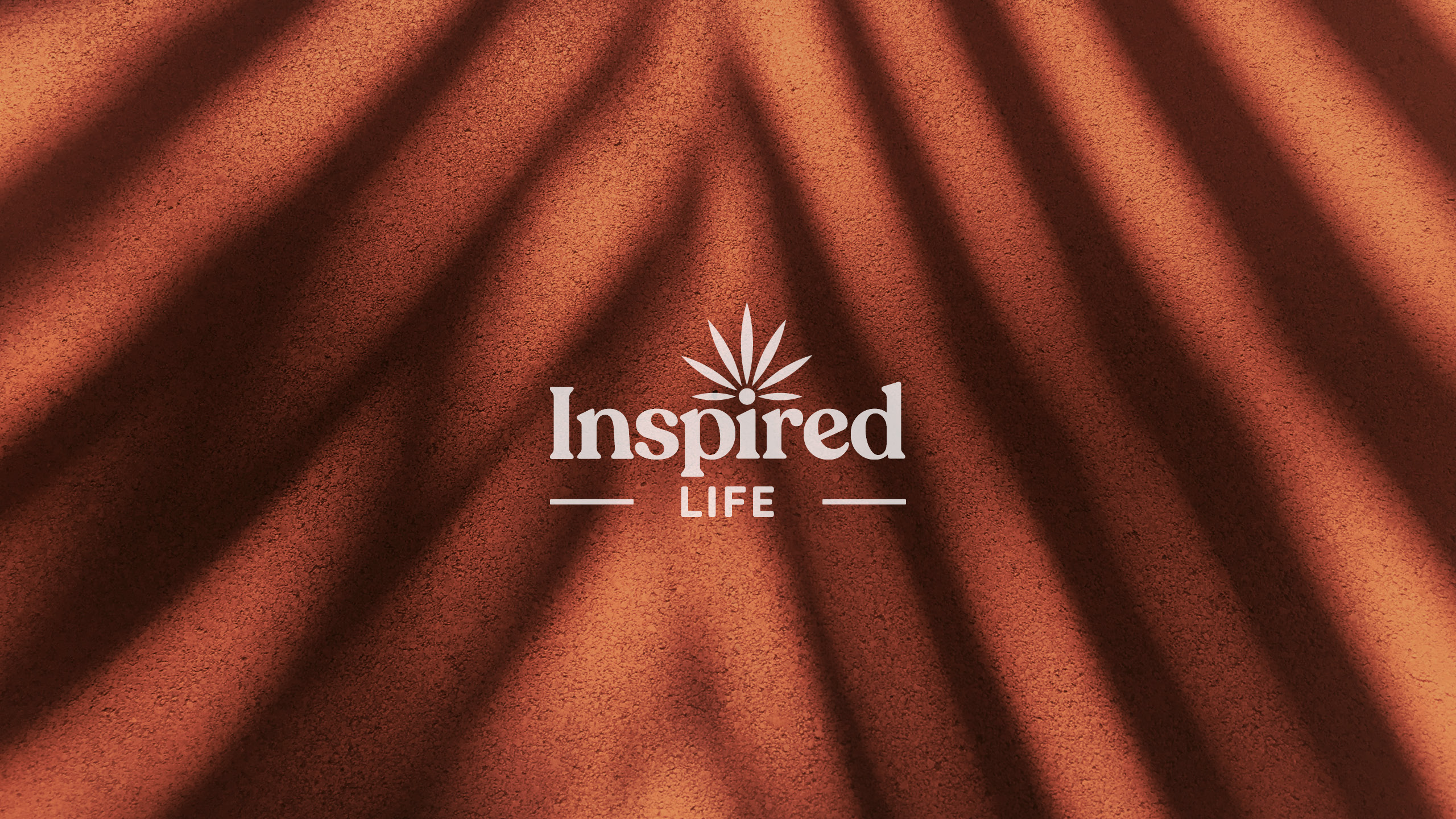 Inspired life logo on orange background with leaf casting a shadow