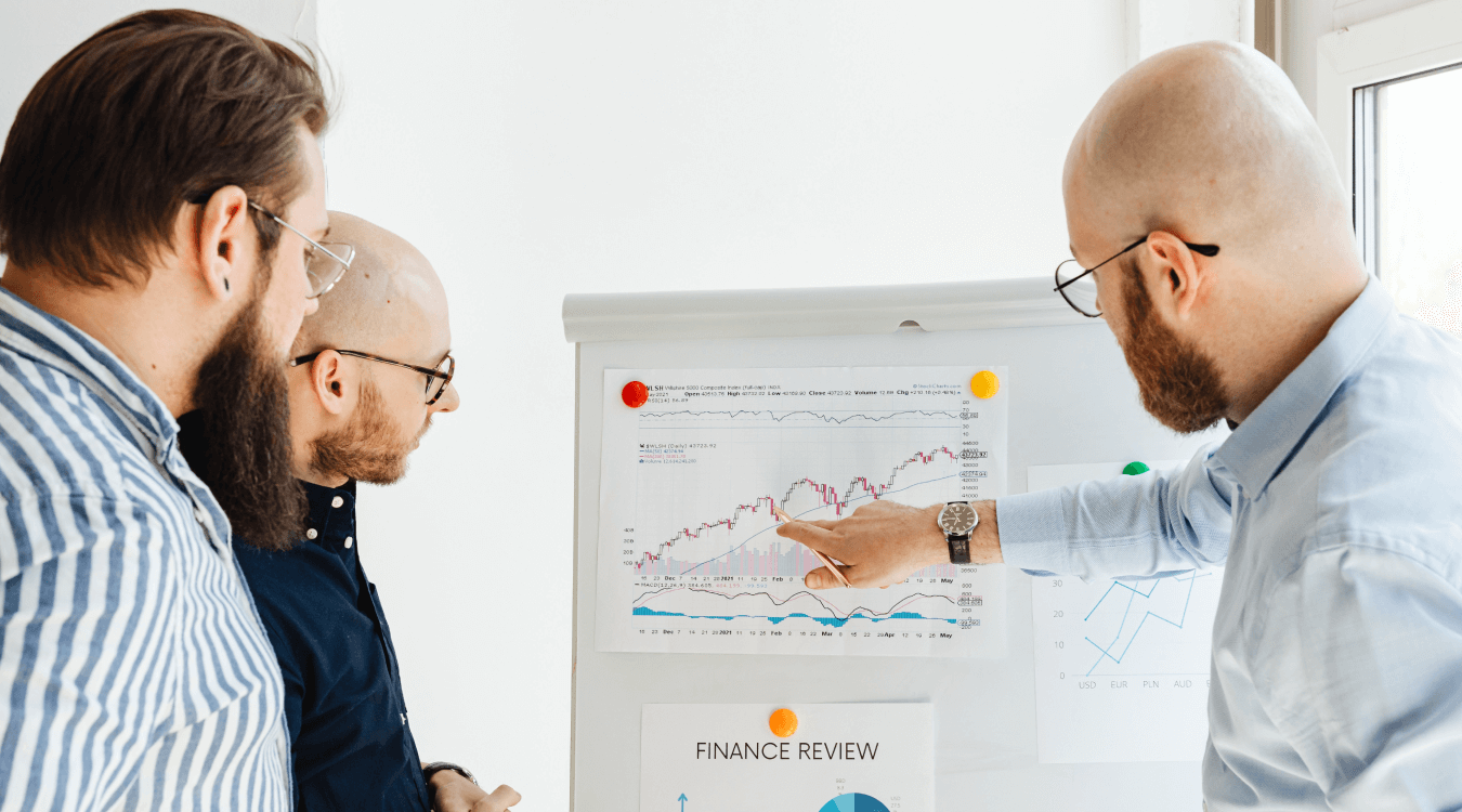 Three businessmen looking at graphs during a finance review to reconsider their spending