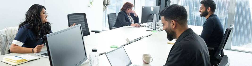 four people working at their desk in an office environment