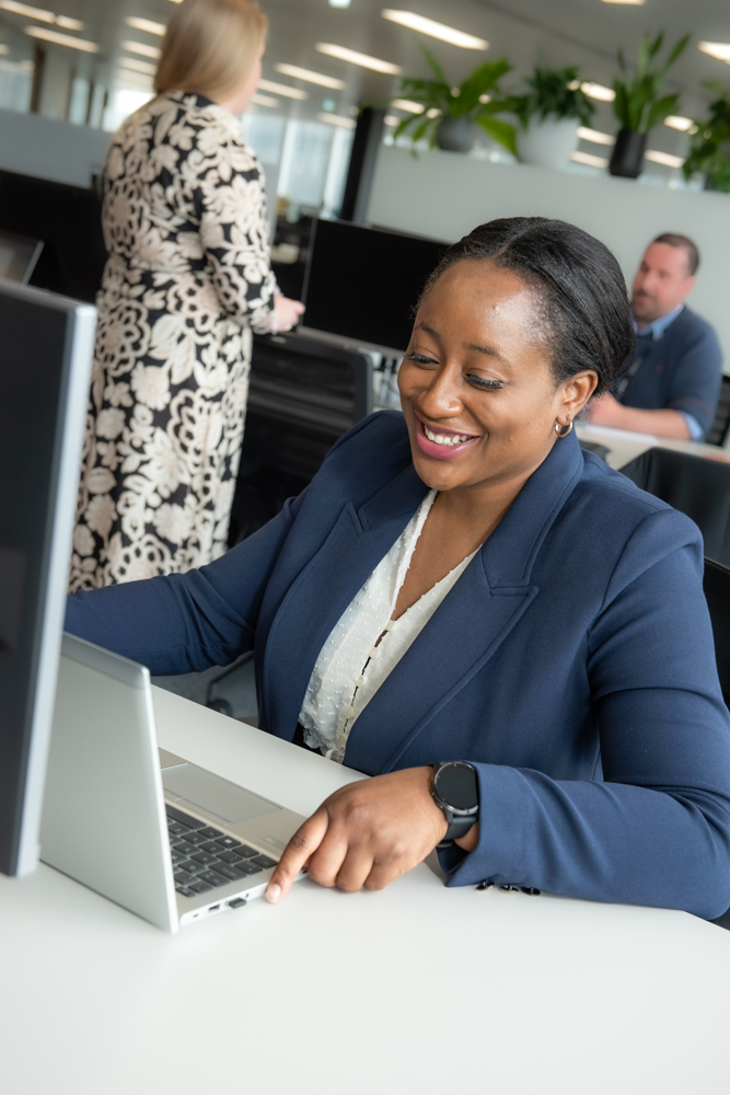 One of our colleagues smiling while working on her laptop