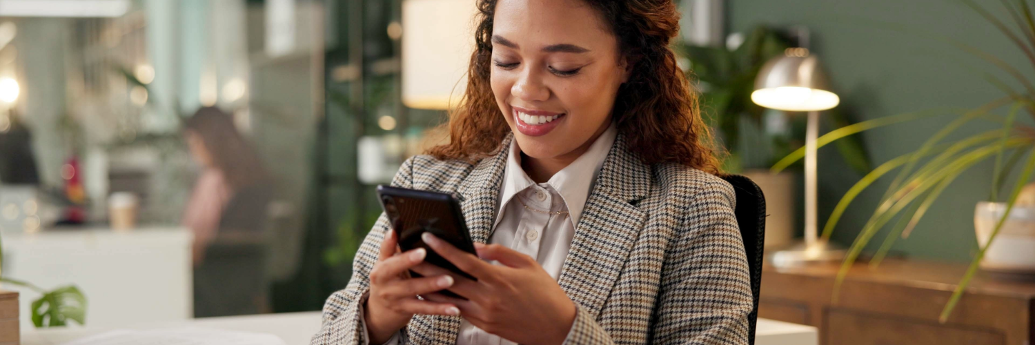 A woman types on a phone while smiling