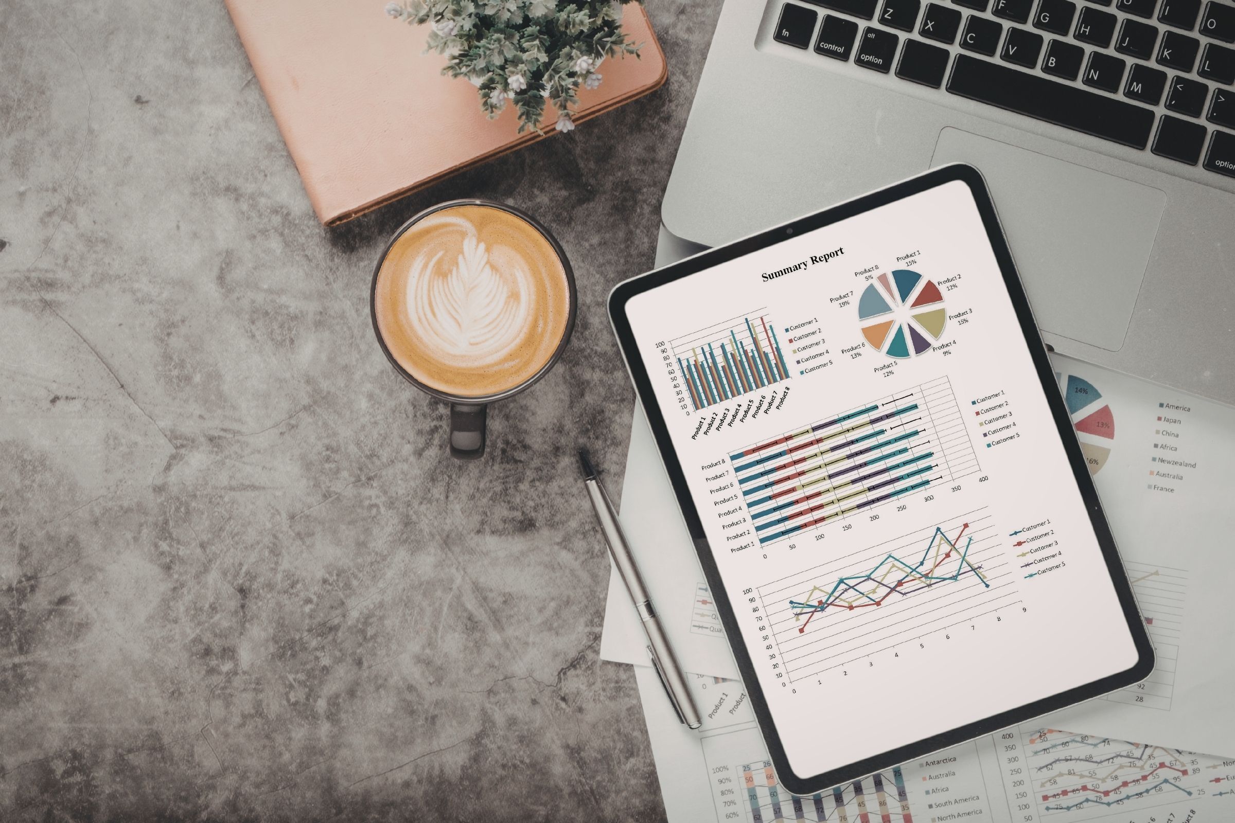 Stack of SEO reports beside a laptop and a cup of coffee on a work desk