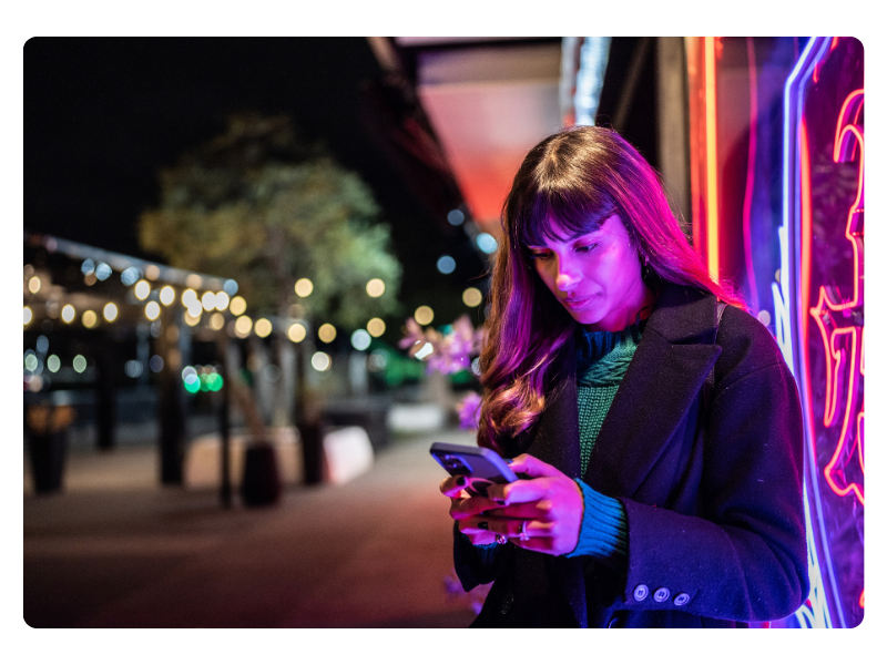A woman checks her phone at night