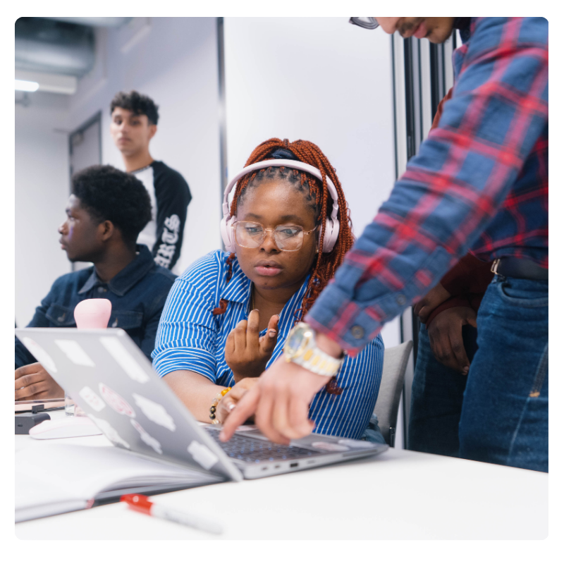 A man helps a young girl on a laptop
