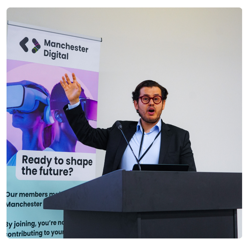 A speaker on stage raises his hand