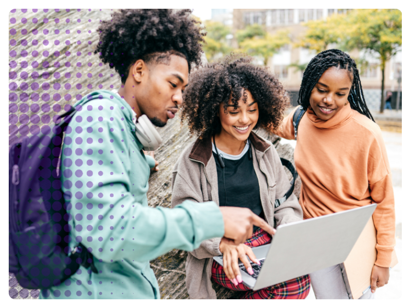 Three young people gather around a laptop outside