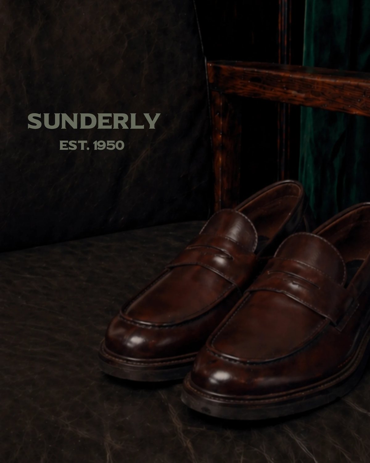 SUNDERLY key visual: brown penny loafers on a leather chair by dark wood and velvet, with the lettering, AI concept work