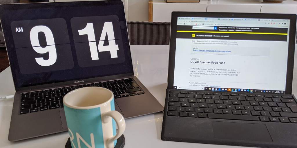 Two laptops and a mug on a table. One laptop has the GOV.UK COVID summer Food Fund webpage open.