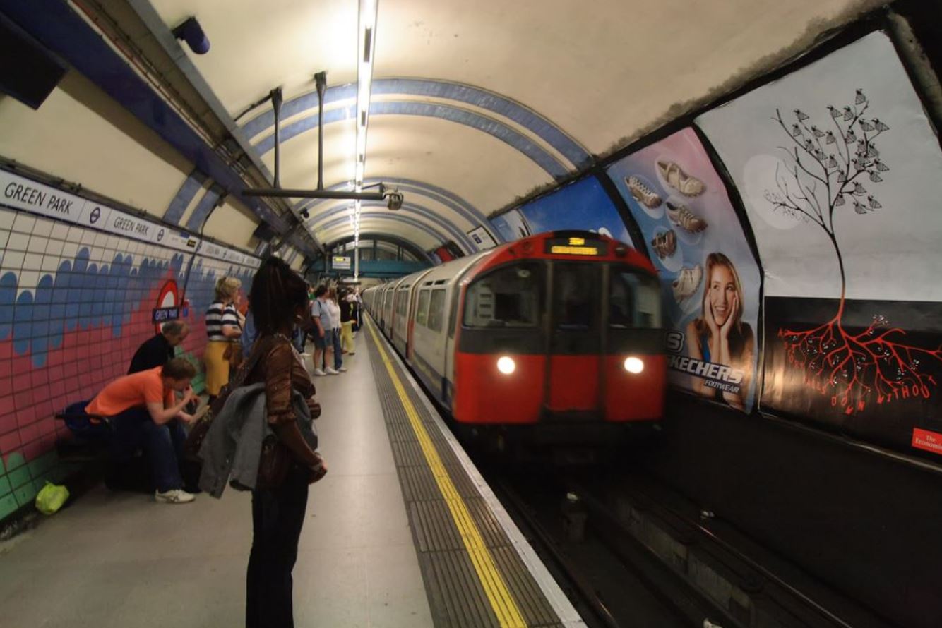 Woman standing on Green Park tube station platform as a tube passes by