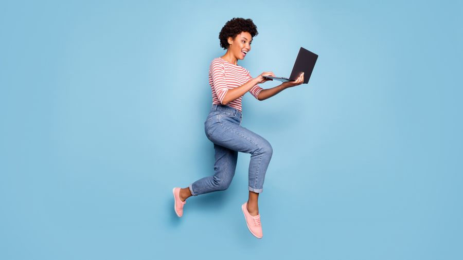 woman jumping holding laptop