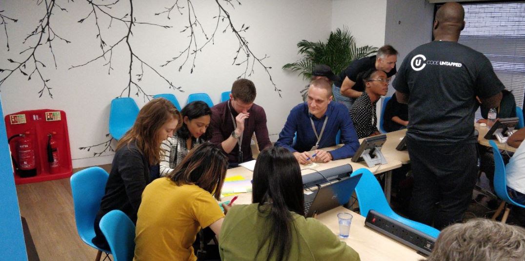 About 10 people sitting in a group concentrating and conferring.