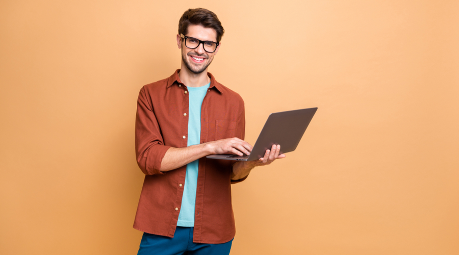 Man smiling using laptop on bright background