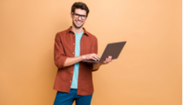 Man smiling using laptop on bright background