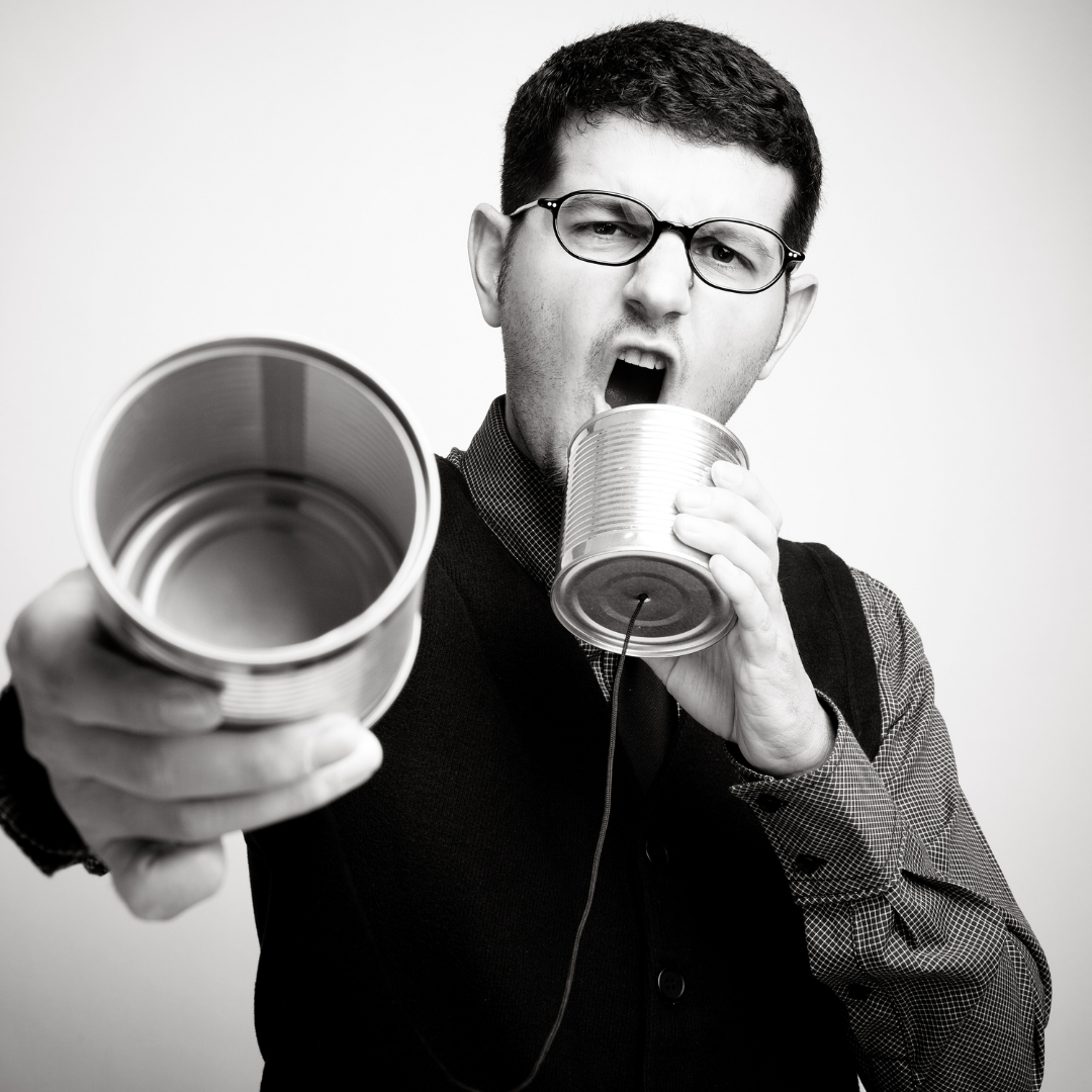 Man holding a tin cup out and talking into it.